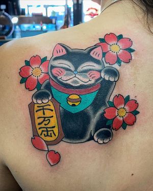 Admire Eddy Ospina's masterful blend of Japanese lettering and illustrative style in this stunning upper back tattoo featuring a lucky manekineko surrounded by delicate sakura flowers.