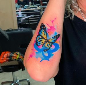 Captivating forearm tattoo by Marcel Oliveira, showcasing a colorful illustrative butterfly design.