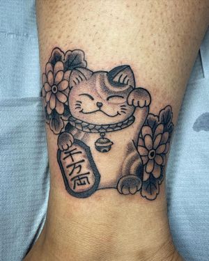 Eddy Ospina's captivating tattoo features a mystical cat, delicate flower, manekineko, and powerful kanji symbols in bold blackwork style.