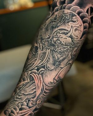 Experience the power of a blackwork Japanese dragon and Raijin tattoo by renowned artist Ami James, featuring intricate illustrative clouds.
