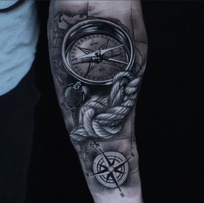 A beautifully detailed compass and map tattoo with a meaningful quote, expertly crafted in black and gray by Marcel Oliveira on the forearm.