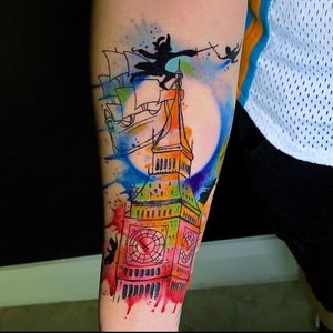 Vibrant forearm tattoo by Marcel Oliveira featuring a ship, sword, watch, clock, and tower.