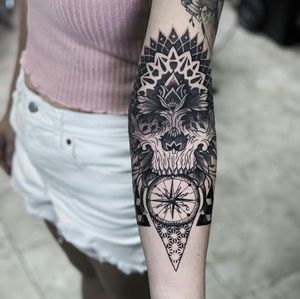 Blackwork and dotwork forearm tattoo featuring an intricate design of a skull, compass, and mandala pattern by Marcel Oliveira.