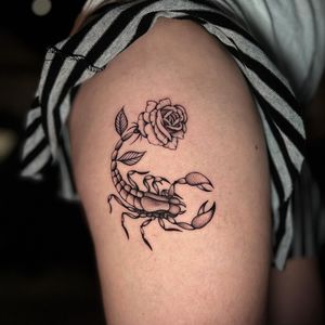 Unique blackwork tattoo featuring a scorpion and flower design on the upper leg, expertly done by tattoo artist Chris Tambo.