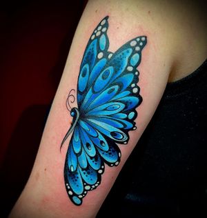 Elegant butterfly tattoo on upper arm by renowned artist Darren Brass, showcasing his expert illustrative style.