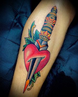 Get an illustrative lower leg tattoo of a flower, heart, and dagger by the talented artist Darren Brass.