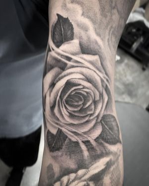 Adorn your arm with a stunningly detailed flower tattoo by Rico Dionichi. The black & gray realism style is sure to make a bold statement.