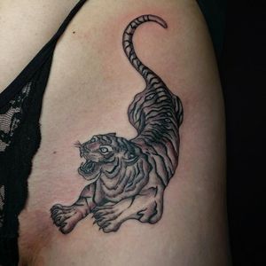 Get wild with this striking upper leg tattoo of a tiger in black and gray, expertly done by Fernando Joergensen.