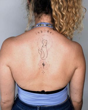 Embrace the magic with this fine line upper back tattoo featuring a beautiful mermaid surrounded by moons, circles, and intricate patterns. By Gabriele Edu.