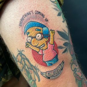 Fine line illustrative tattoo of Milhouse as a kid with glasses and a small lettering quote, on lower leg by Jethro Wood.