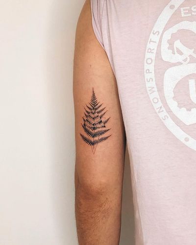 Fine line illustration of a tree inside a geometric triangle, on the upper arm. Created by Gabriele Edu.