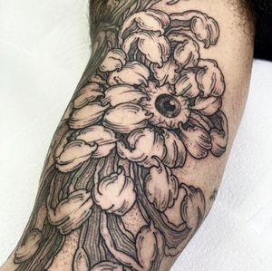 Exquisite upper arm tattoo featuring a chrysanthemum flower and eyeball in fine line Japanese style. Designed by artist Lamat.