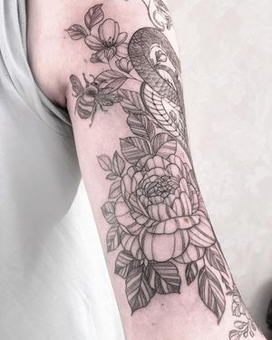 This stunning blackwork and fine line tattoo features a intricate design of a snake, bee, and flower. Created by the talented artist Alisa Hotlib.