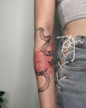 Get mesmerized by Anna's stunning illustrative design combining a snake and chrysanthemum on your forearm.