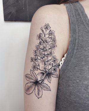 Anna's stunning blackwork flower tattoo on the upper arm showcases intricate illustrative details.