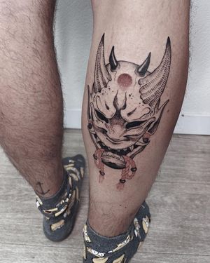 Illustrative tattoo by Anna featuring a hannya mask with ropes and horns, beautifully executed on the lower leg.