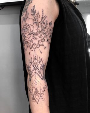 Blackwork fine line design by Alisa Hotlib on forearm combining flower motifs with intricate patterns.