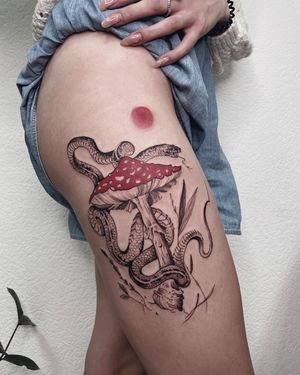 Unique blackwork and illustrative design by Anna, featuring a snake and mushroom motif on the upper leg.