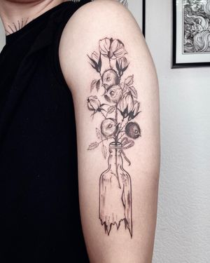 Anna's illustrative design featuring a bird, flower, bottle, and rope on the upper arm.