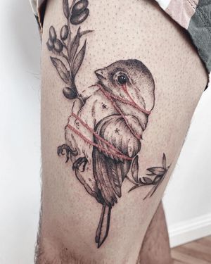 A striking blackwork tattoo on the upper leg featuring a bird, flower, and rope, expertly done by artist Anna.