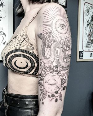 Explore the mystical world with this fine line blackwork upper arm tattoo featuring a moon, snake, and intricate geometric patterns by Alisa Hotlib.