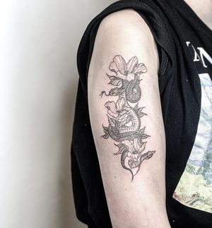 A striking combination of a snake and a flower in an illustrative blackwork style, tattooed on the upper arm by Alisa Hotlib.