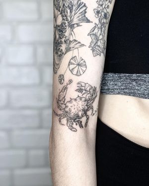 Experience the detailed artistry of Alisa Hotlib's blackwork tattoo featuring a beautiful flower, crab, and sprig design on your forearm.