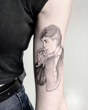 Impressive blackwork and realistic tattoo of man in suit smoking a cigarette by artist Alisa Hotlib on upper arm.