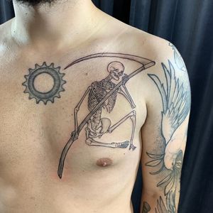 Get a striking blackwork skeleton and scythe tattoo on your chest by the talented artist Slava. Embrace the powerful imagery of life and death.