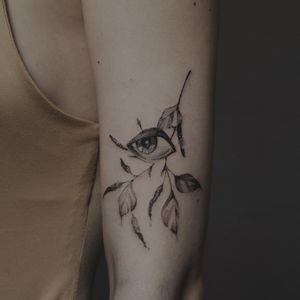 Get mesmerized by Alisa's stunning blackwork and illustrative design featuring a leaf and eye on your upper arm.