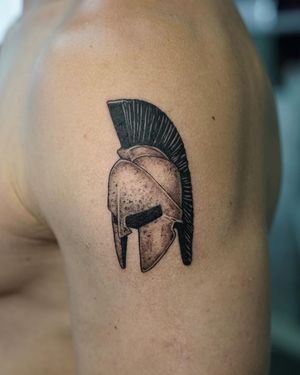Get a bold blackwork helmet tattoo on your upper arm, created by Lim's skilled hand. Unique and detailed design that stands out.
