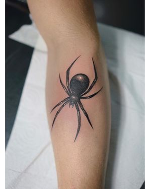 A bold blackwork spider tattoo on the forearm, created by Lim with intricate illustrative details.