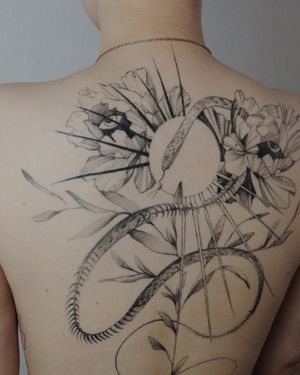 Beautiful blackwork back tattoo featuring a sun, snake, flower, eye, and intricate patterns by Alisa.