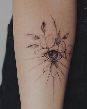 Illustrative upper arm tattoo featuring a stunning flower and eye design by Alisa.