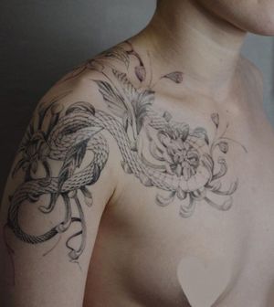 Adorn your shoulder with a stunning blackwork snake and flower design by Alisa, blending elegance and nature.