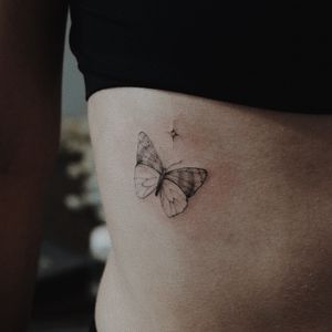 Beautiful illustrative butterfly tattoo by Alisa, placed on the ribs for a bold and stunning look.
