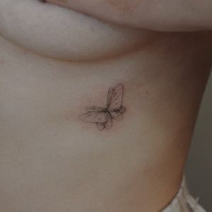 Elegantly detailed fine line butterfly tattoo on the ribs by artist Alisa. Bring a touch of nature and beauty to your body.