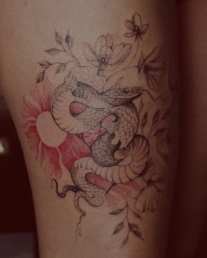 Embrace the power of nature with this striking blackwork tattoo featuring a sun, snake, and flower. By the talented artist Alisa.