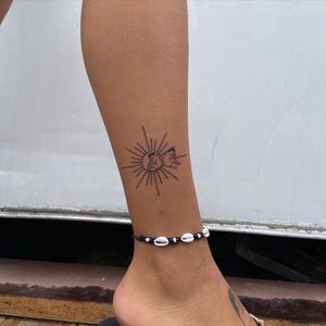 Fine line and illustrative design by Karyna, combining a sun motif with intricate geometric patterns on the ankle.