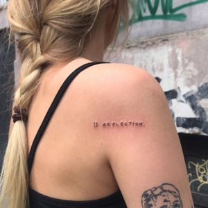 Get inspired with Karyna's fine line and small lettering upper back tattoo featuring a meaningful quote.