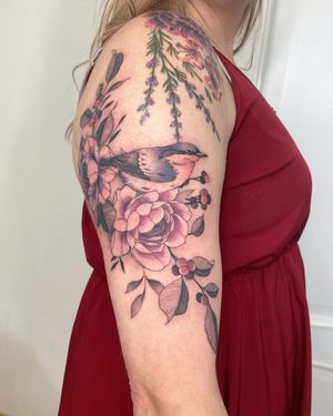 Beautiful neo-traditional tattoo by Kasia on upper arm, featuring a stunning bird and flower illustration.