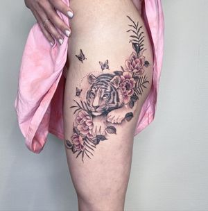 Unique upper leg tattoo by Kasia, combining ornamental blackwork style with tiger, butterfly, and flower motifs.