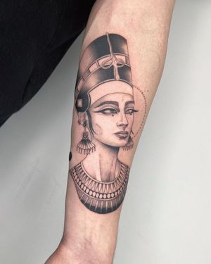 This striking blackwork tattoo by Kasia features a woman with a hat, earrings, and necklace on the forearm.
