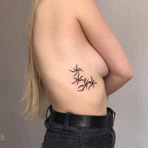 Discover intricate blackwork design with geometric patterns and delicate flowers on your ribs by talented artist Karyna.