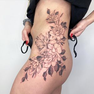 Elegantly detailed blackwork and fine line design on upper leg by Kasia, combining fish and floral motifs.