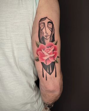 Baingio's blackwork and watercolor tattoo features a woman with flowers and hints of blood on the upper arm.
