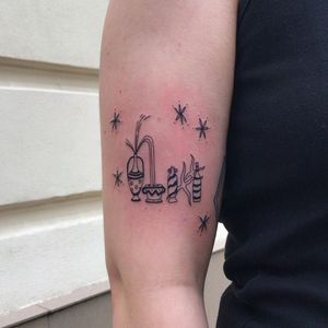Elegant upper arm tattoo featuring a star, vase, and bottle in fine line illustrative style, created by the talented artist Karyna.
