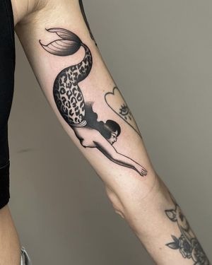 Get a stunning blackwork mermaid tattoo on your forearm, executed in a traditional illustrative style by the talented artist Joanna.