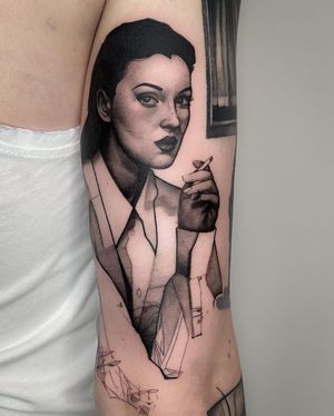 Upper arm blackwork tattoo of a woman elegantly holding a cigarette, done by Joanna.