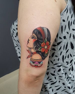 Get inked with a beautiful illustrative tattoo of a flower woman with earrings on your upper arm, done by artist Dorota.